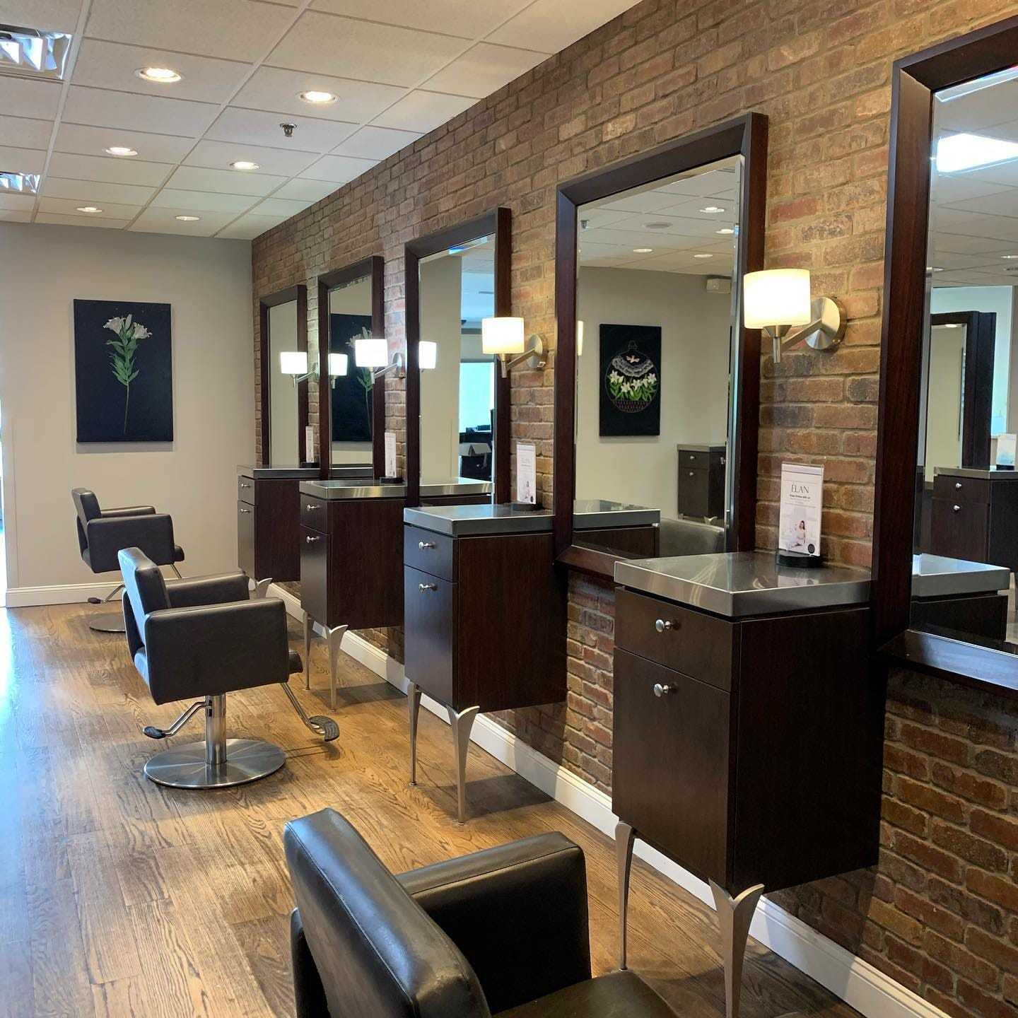 Modern hair salon with brick walls, stylish chairs, and mirrored stations.